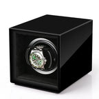 Aevitas single watch winder in high-gloss piano black with a silver interior holding a green-faced automatic watch.