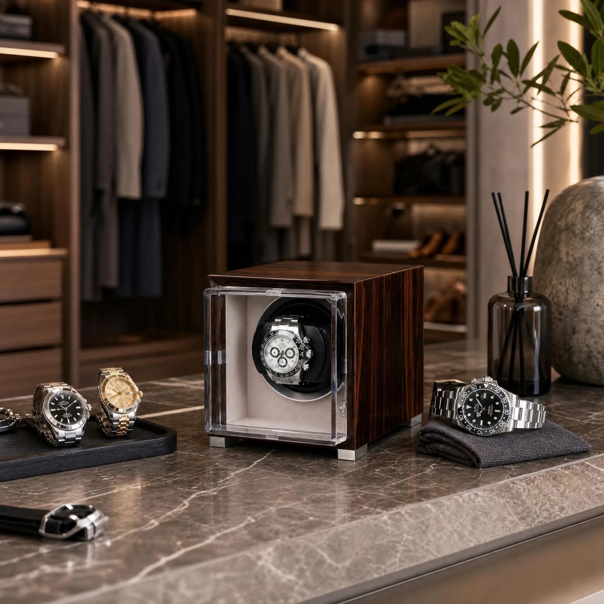 Single watch winder in glossy ebony Macassar wood with a clear glass display case, housing a luxury chronograph watch.