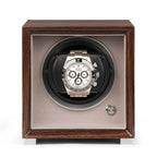 Single watch winder in glossy ebony Macassar wood finish with a silver-faced chronograph watch on a soft beige interior.