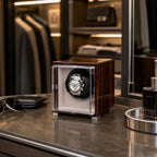 Single watch winder in glossy ebony Macassar wood finish with a clear display case holding a luxury automatic watch.