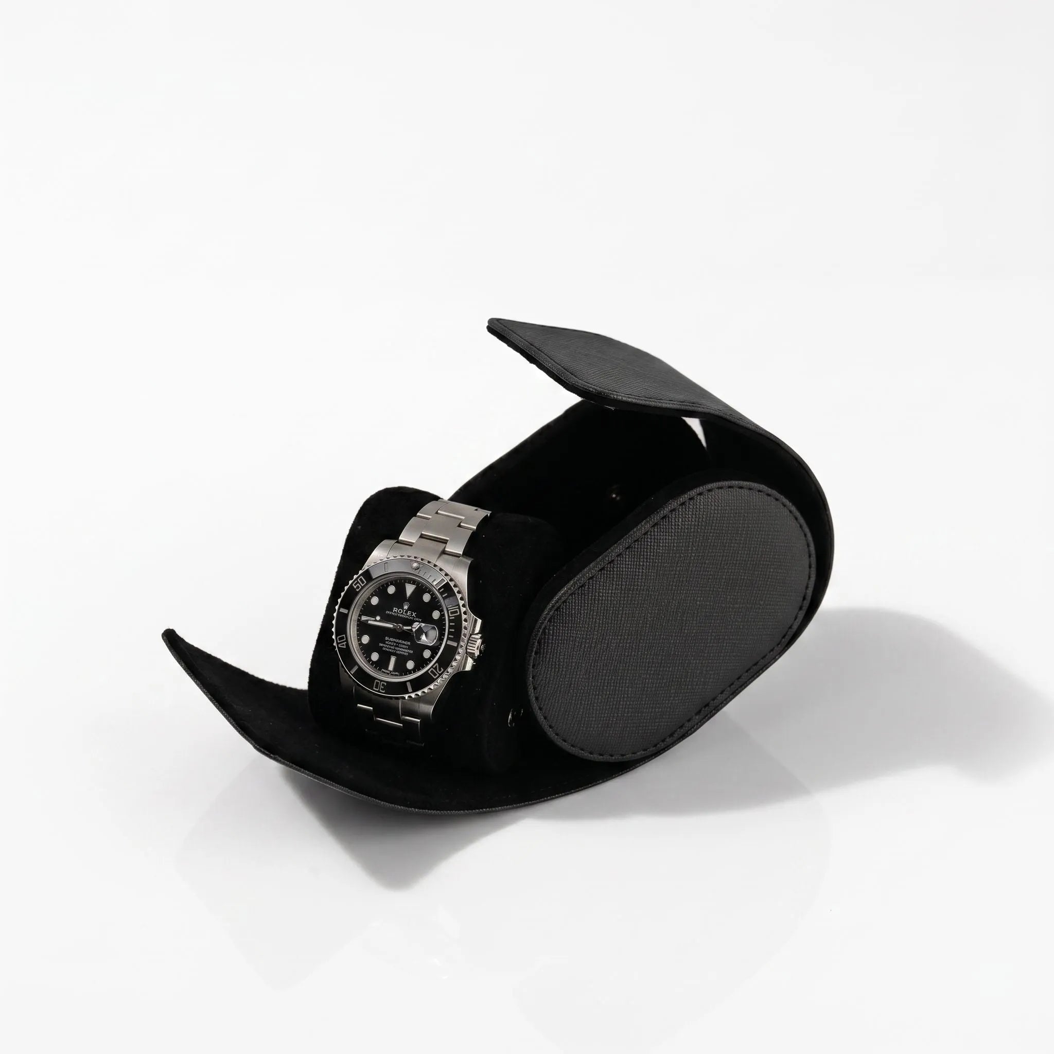 Close-up of black saffiano vegan leather watch roll with soft lining, showcasing micro-texture and gentle lighting on a clean surface.