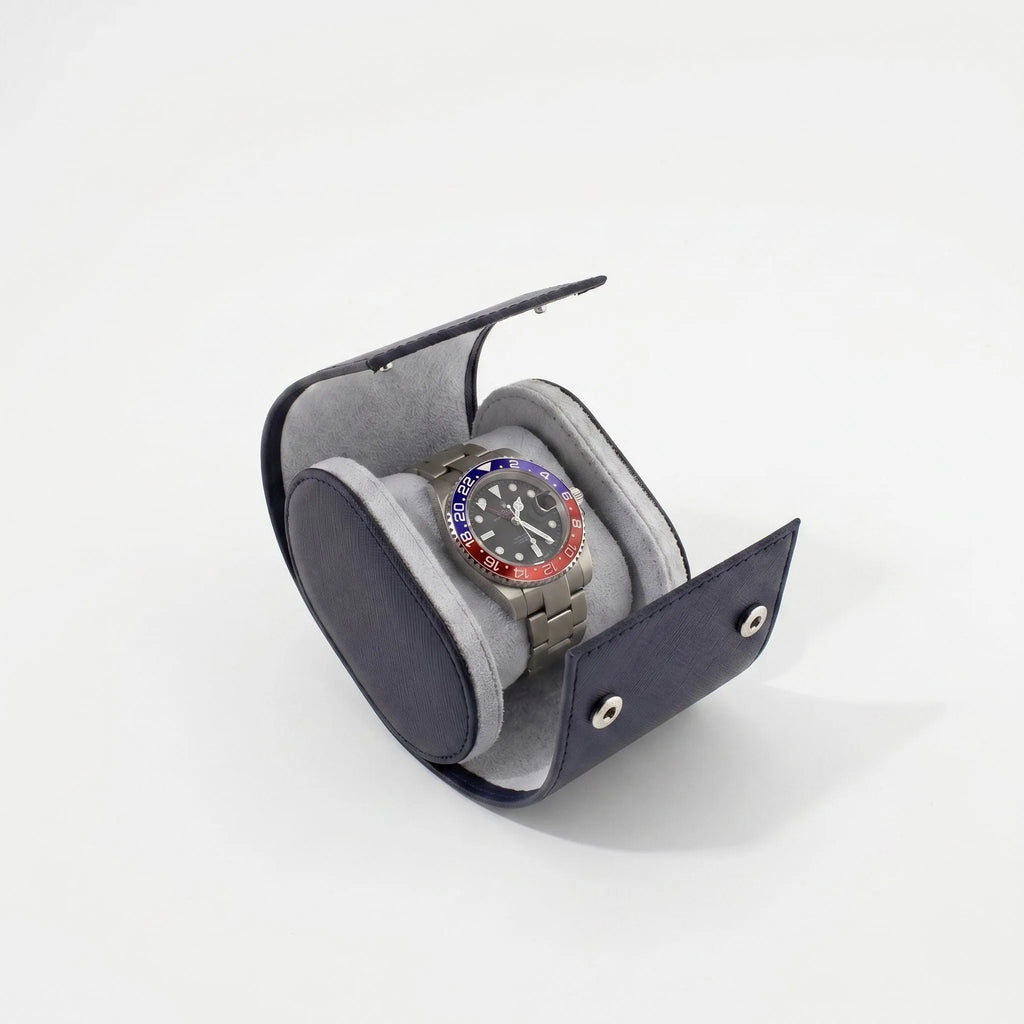 Close-up of navy blue saffiano leather watch roll with soft lighting and subtle shadow on a white background.