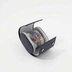 Close-up of navy blue saffiano leather watch roll with soft lighting and subtle shadow on a white background.