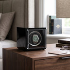 Aevitas single watch winder in high gloss black with a green automatic watch, displayed on a wooden bedside table.