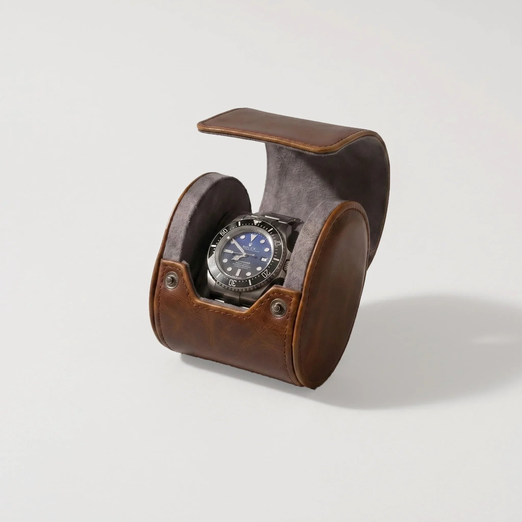 Vintage brown vegan leather single watch roll with grey suede lining, holding a silver watch.